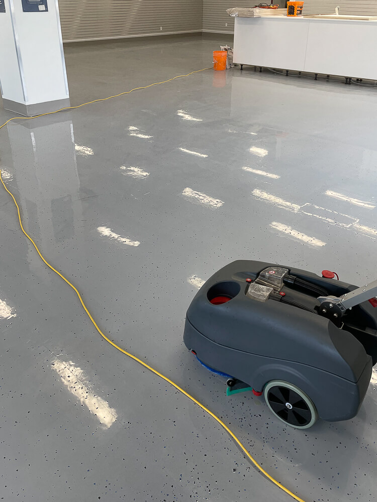 Shiny hard floor with a cleaning machine and yellow power cord.