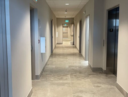 Bright, sanitized commercial hallway with tile flooring and elevator access in a Hamilton L8L office facility
